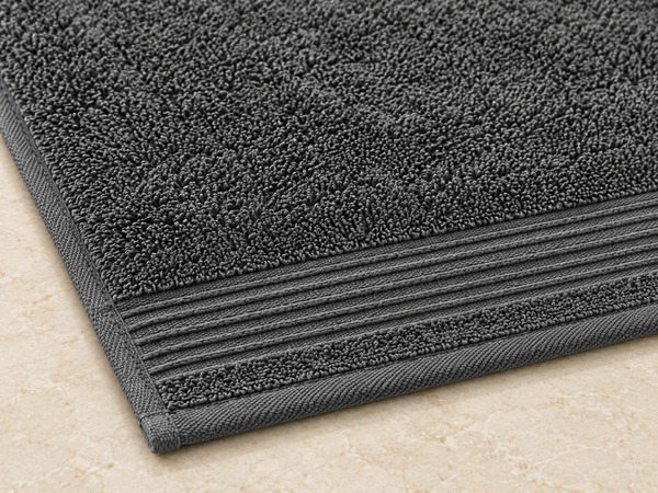 Corner of a dark gray towel showing the woven border and finished edge.