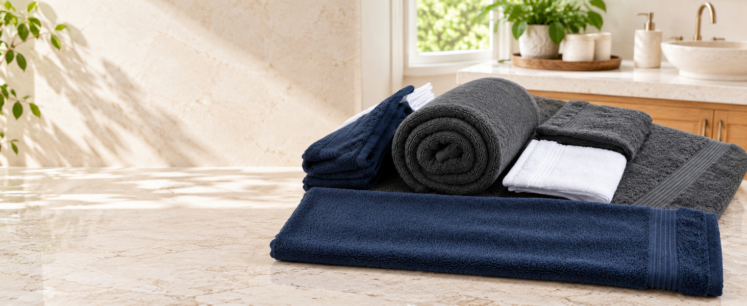 White, dark gray, and navy Denica Home cotton towels arranged in a bright modern bathroom.