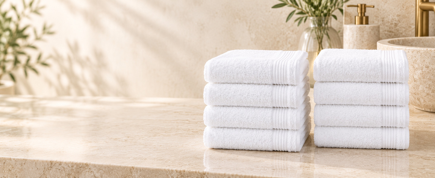 Two stacks of four white washcloths on a marble counter.
